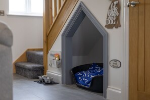 A dog house with a sign reading "The Dog House" and a dog bowl on the floor.