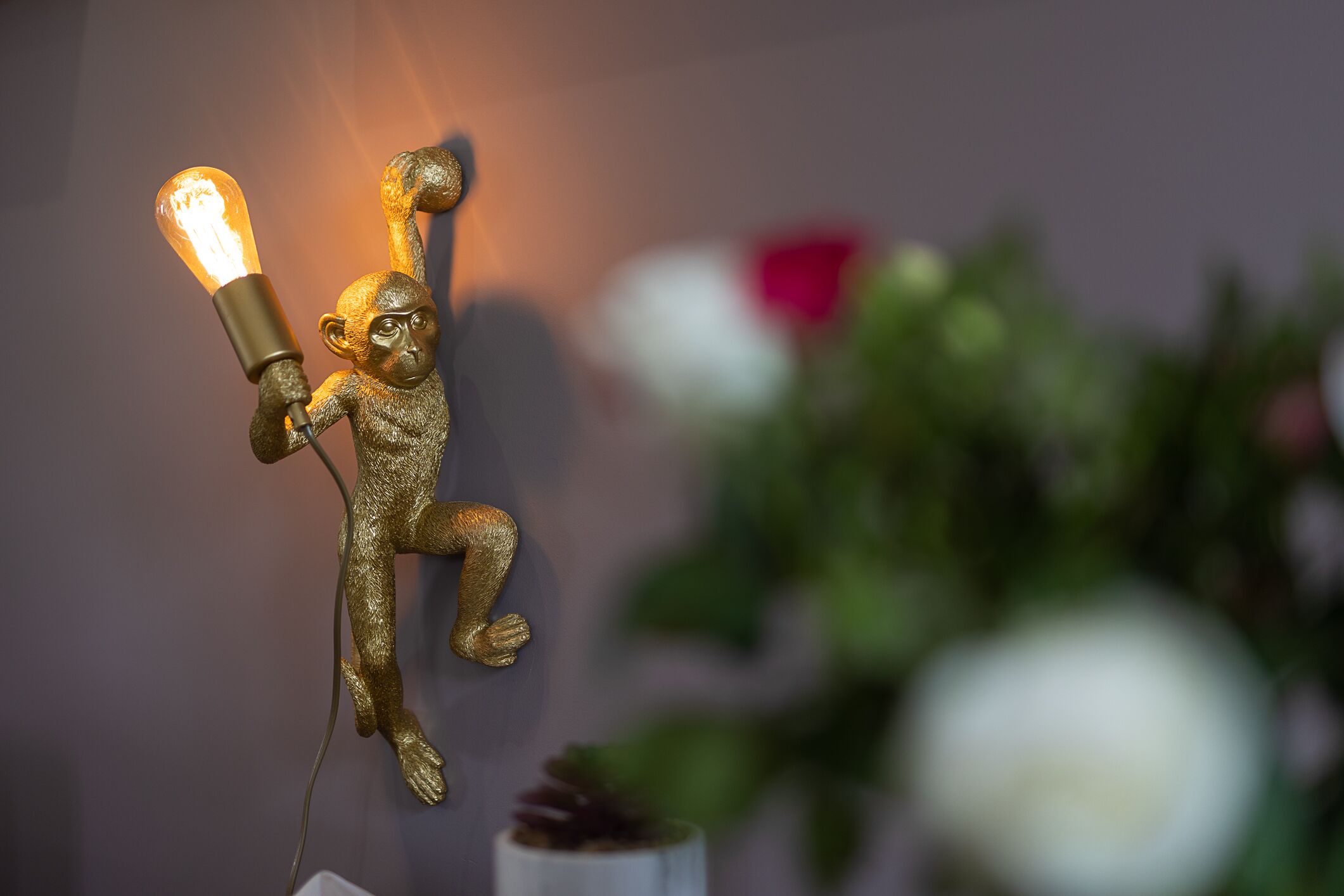 A decorative monkey figurine holding a light bulb, mounted on a wall.