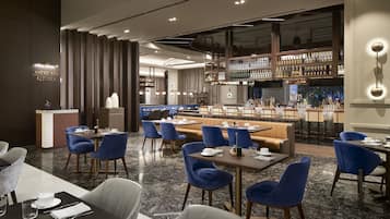 A modern restaurant with a bar area, seating arrangements, and a visible kitchen.