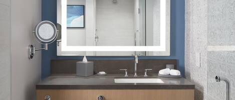 A modern bathroom with a large mirror, a sink, a towel rack, and a shower area.