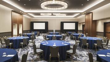 A conference room with round tables, chairs, and a large screen.