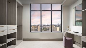 Una habitación moderna con un amplio ventanal, estanterías empotradas y vistas a la ciudad.