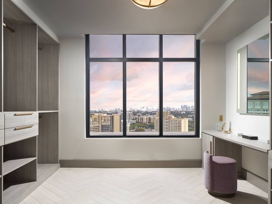 Una habitación moderna con un amplio ventanal, estanterías empotradas y vistas a la ciudad.