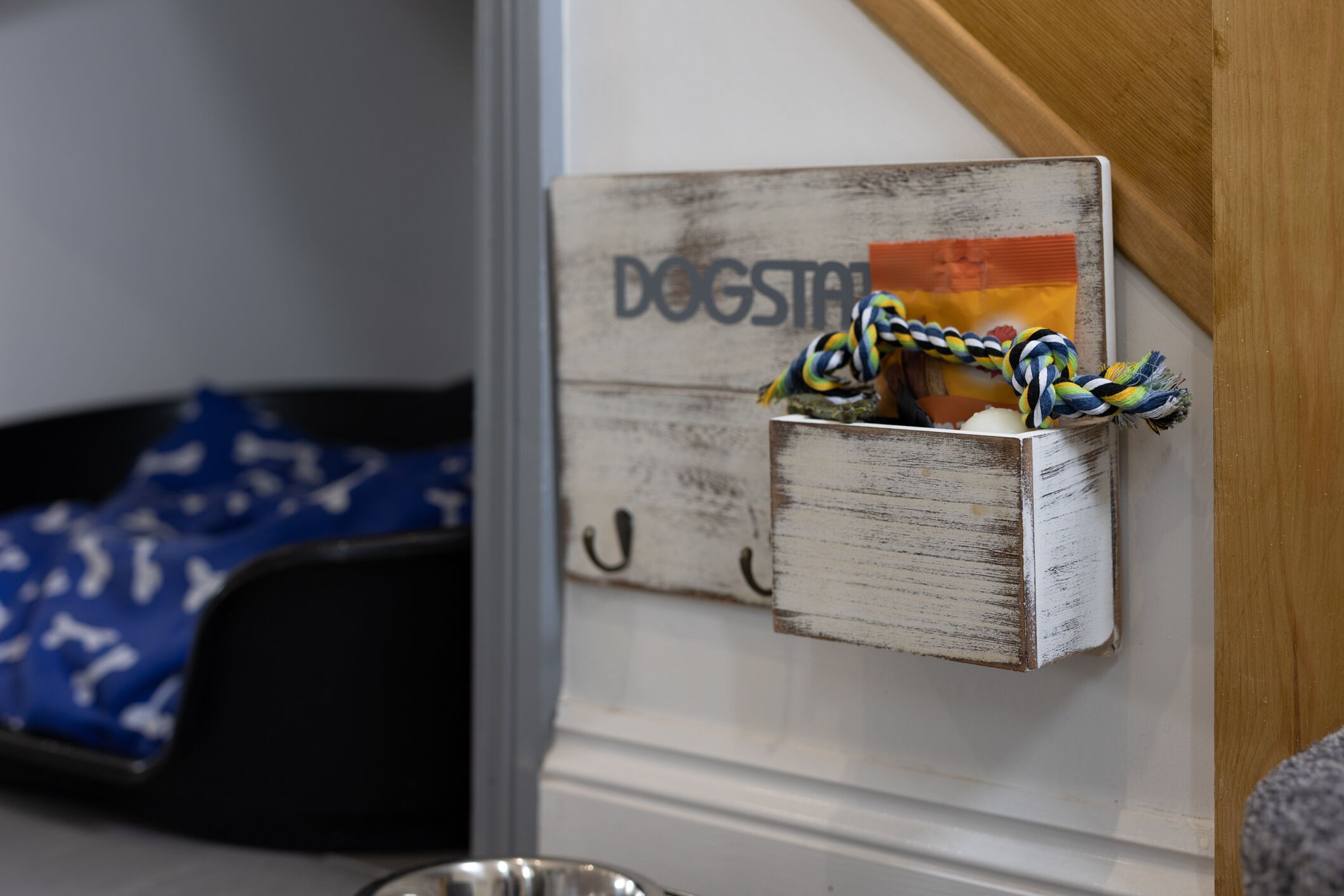 Une niche pour chien rustique, à fixer au mur, avec un jouet en corde et une carte.