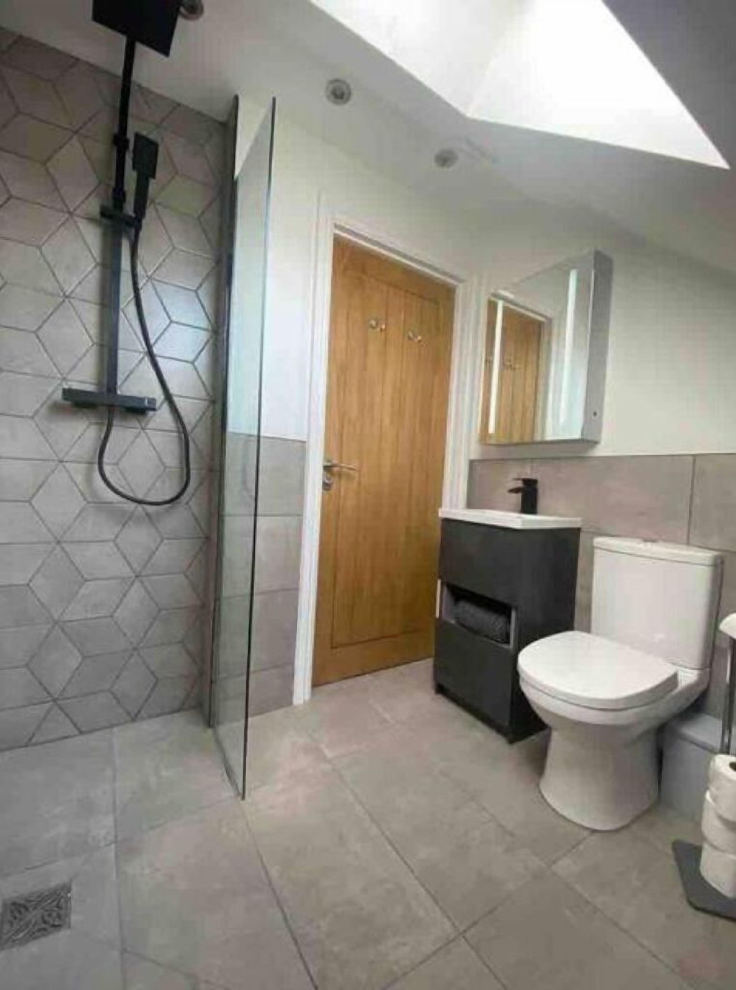 A modern bathroom with a shower, toilet, and sink.