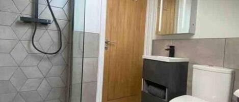 A modern bathroom with a shower, toilet, and sink.