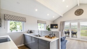 A modern kitchen with a central island, large windows, and a cozy seating area with a view. - Throstle Nest Farm Lodges (Skipton)