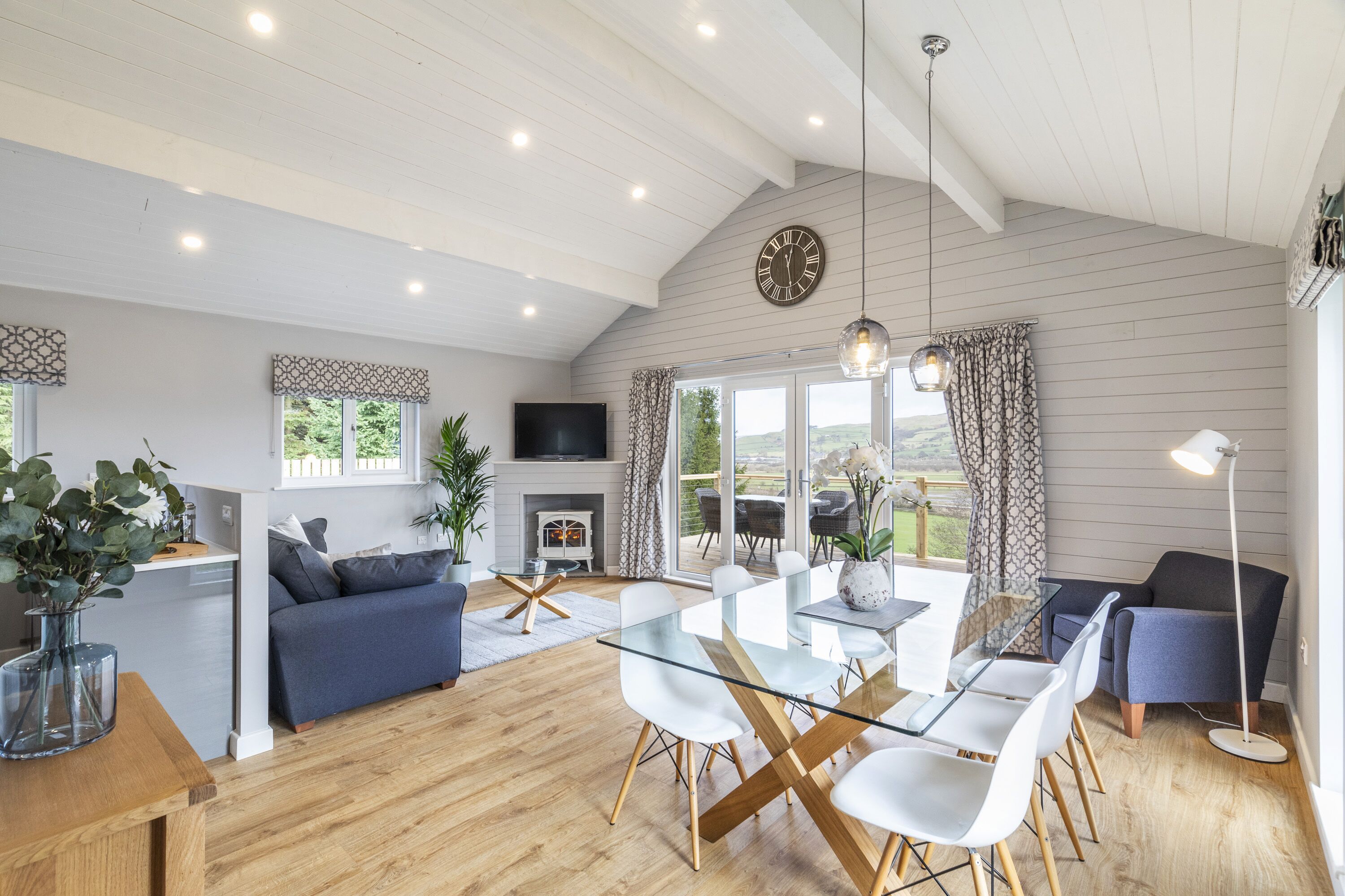 A spacious living area with a glass dining table, sofas, and a fireplace.