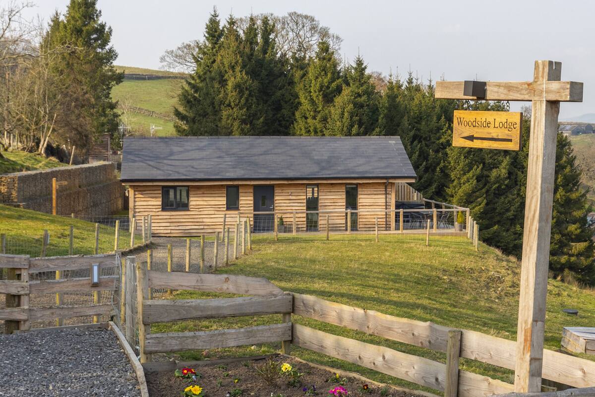 A wooden lodge with a sign indicating the direction to Woodside Lodge.