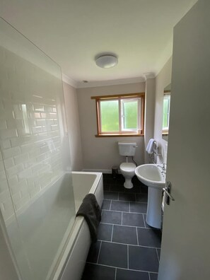Un baño con bañera, inodoro y lavamanos.