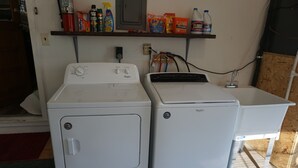 Two front-loading washers and a sink in a laundry area with shelves above holding cleaning supplies. - Cozy house  close to public land areas for recreation! (West Mineral)