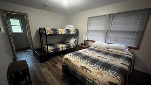 A bedroom with a bunk bed, a single bed, a small table, and a window with blinds. - Cozy house  close to public land areas for recreation! (West Mineral)