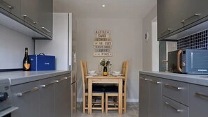 Eine moderne Küche mit grauen Schränken, einem Holztisch und einem Schild an der Wand.