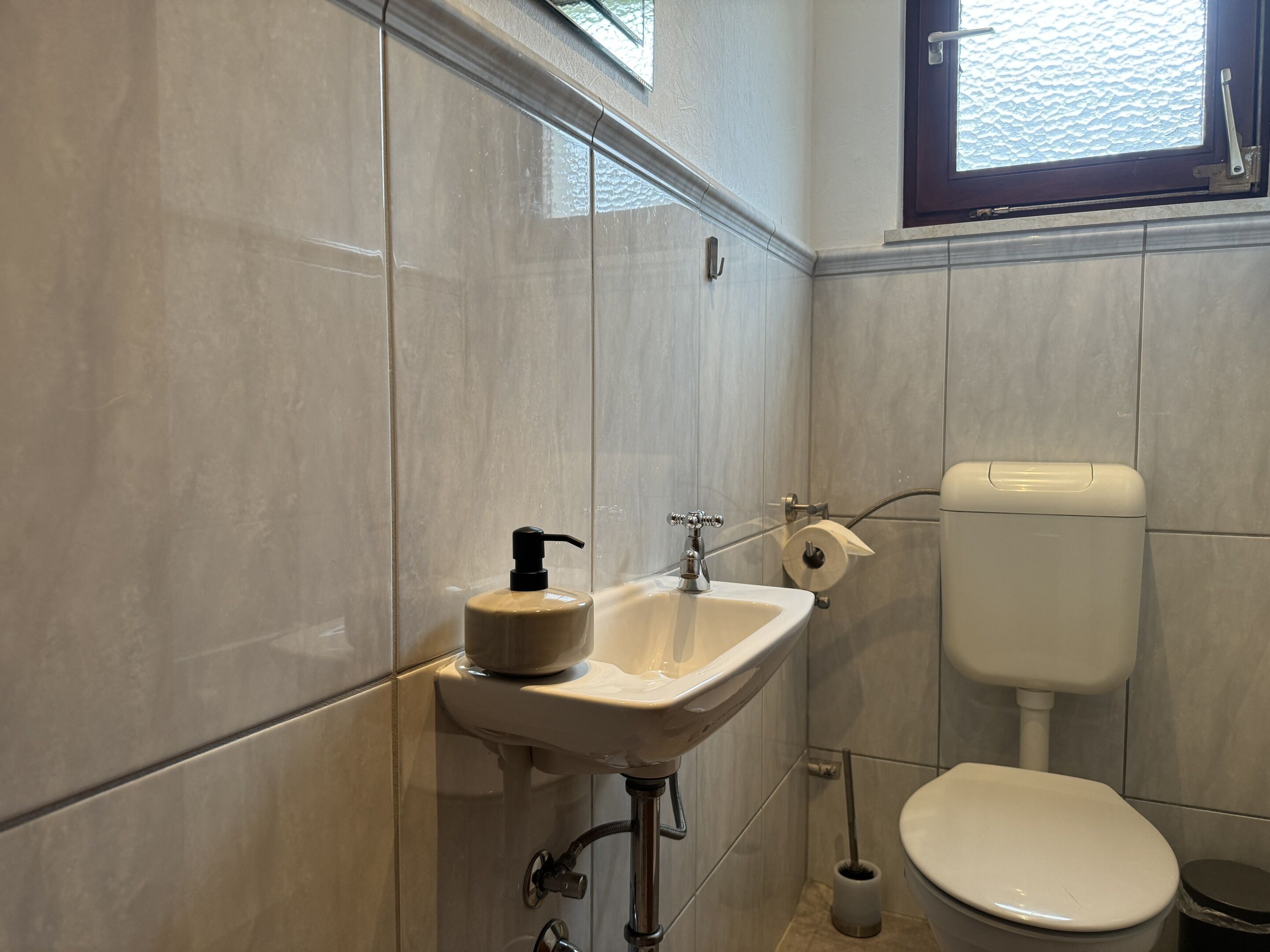 A bathroom with a sink, toilet, and window.