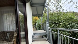 A balcony with a chair, a small table, and a view of greenery. - Ferienhaus Möhrle 4 (Ueberlingen)