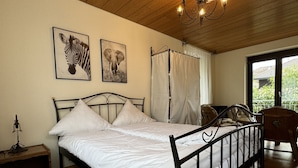 A bedroom with a bed, a nightstand, a lamp, a chandelier, and two framed animal pictures on the wall. - Ferienhaus Möhrle 4 (Ueberlingen)