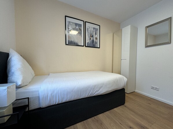 Un dormitorio con una cama, una mesita de noche, un espejo y dos cuadros en la pared.