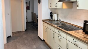 Una cocina estrecha con armarios de colores claros, una encimera de madera y una campana extractora de acero inoxidable.