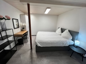 Quarto moderno com cama, escrivaninha e uma cadeira.