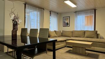 En moderne stue med et glasbord, læderstole, en beige sofa og et træsofabord.