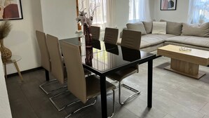 Un moderno salón con una mesa de comedor de vidrio, un sofá color beige y un letrero que dice 'Welcome'.