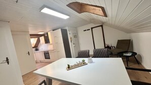 A modern kitchen with white cabinets, a built-in oven, and a dining area with a white table and two chairs. - Ferienhaus Möhrle 7 (Ueberlingen)