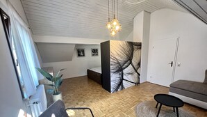 A modern living room with a herringbone floor, a grey sofa, a black armchair, a round rug, and a ceiling light fixture. - Ferienhaus Möhrle 7 (Ueberlingen)