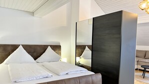 A modern hotel room with a large bed, a dark accent wall, and a large mirror. - Ferienhaus Möhrle 7 (Ueberlingen)