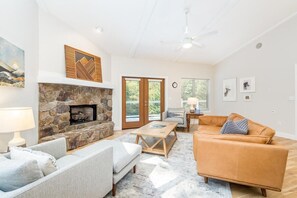 A living room with a stone fireplace, a sofa, a coffee table, and a tan couch.