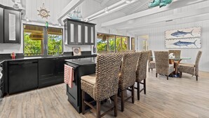A kitchen with a black countertop, wicker chairs, and a dining table with a glass top.