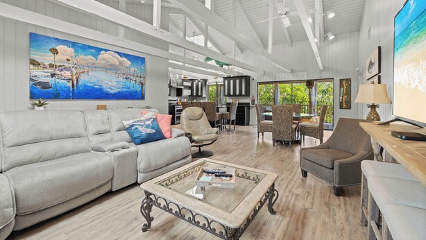 A spacious living area with a large painting, a sofa, a coffee table, and a dining area with chairs.