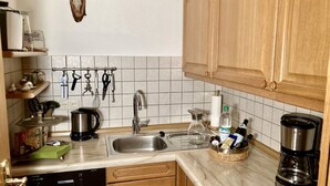 Een keuken met een spoelbak, koffiezetapparaat en keukengerei op het aanrecht.
