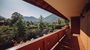 Een balkon met uitzicht op een bergachtig landschap, een stenen trap en een houten leuning.