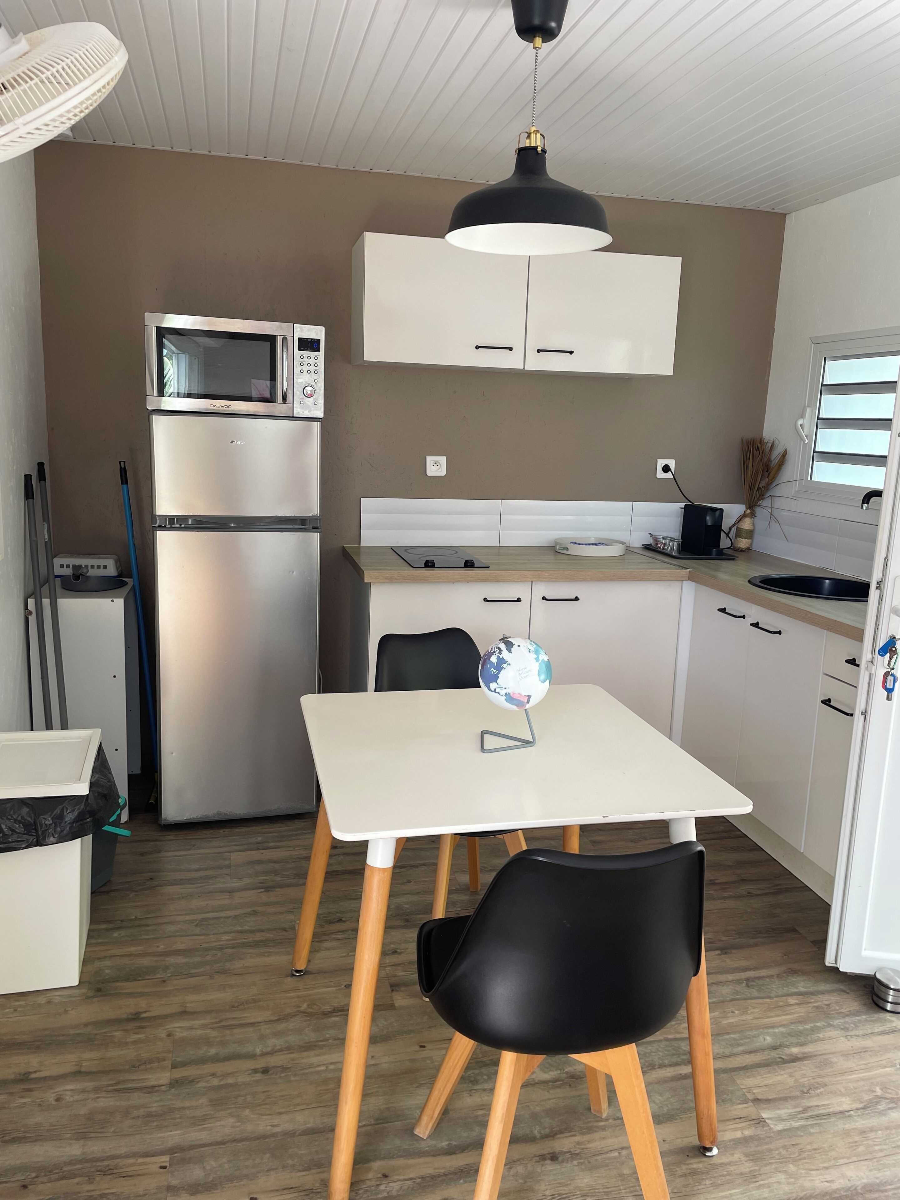 A compact kitchen with a microwave, refrigerator, and a small dining table with chairs.