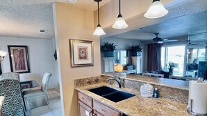 A kitchen with granite countertops, a dishwasher, and a sink. There are pendant lights above the counter. - Harborfront 3BR Retreat (Destin)