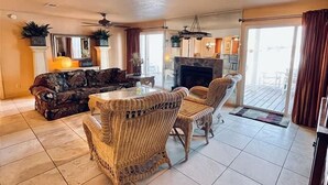 A spacious living room with a fireplace, a dining area, and a balcony with a view. - Harborfront 3BR Retreat (Destin)