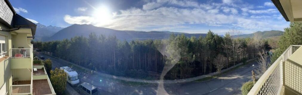 Une vue depuis un balcon donnant sur une route, avec une montagne en arrière-plan.