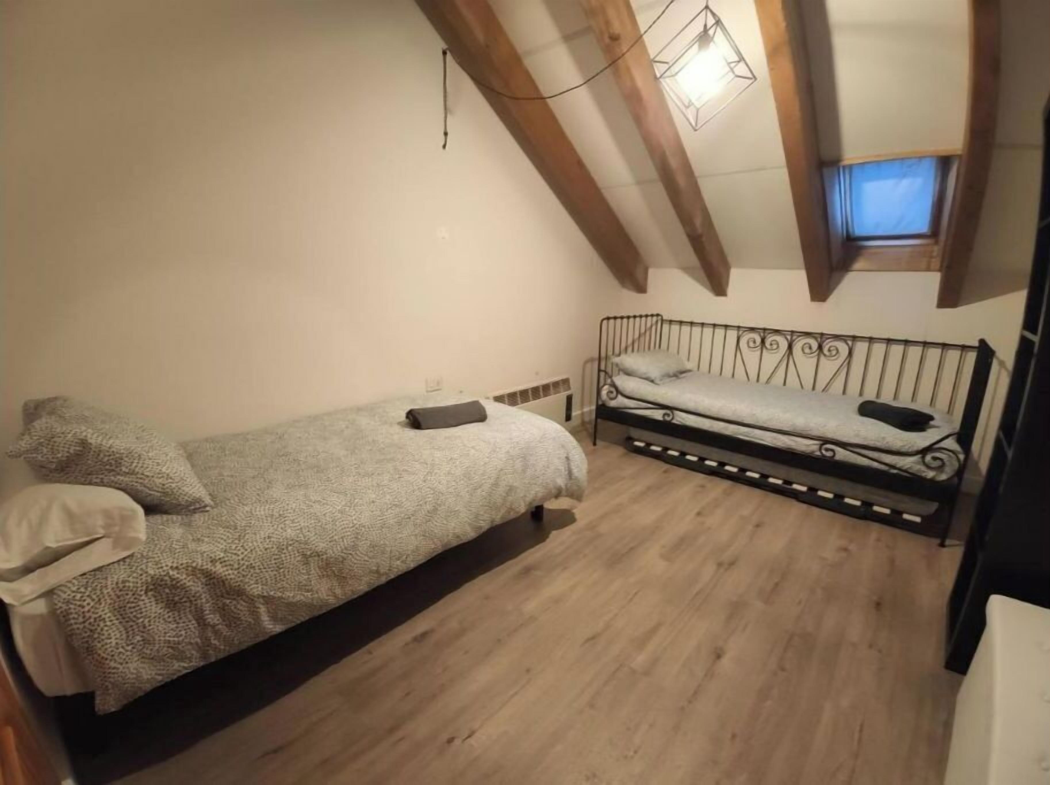 Un apartamento pequeño de una sola habitación con techo estilo loft, una cama, una mesita y un ventanal.