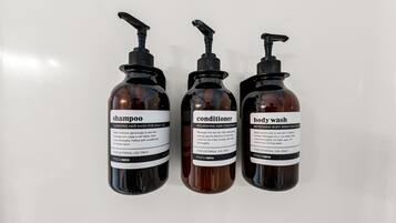 Three bottles of hair care products: shampoo, conditioner, and body wash.