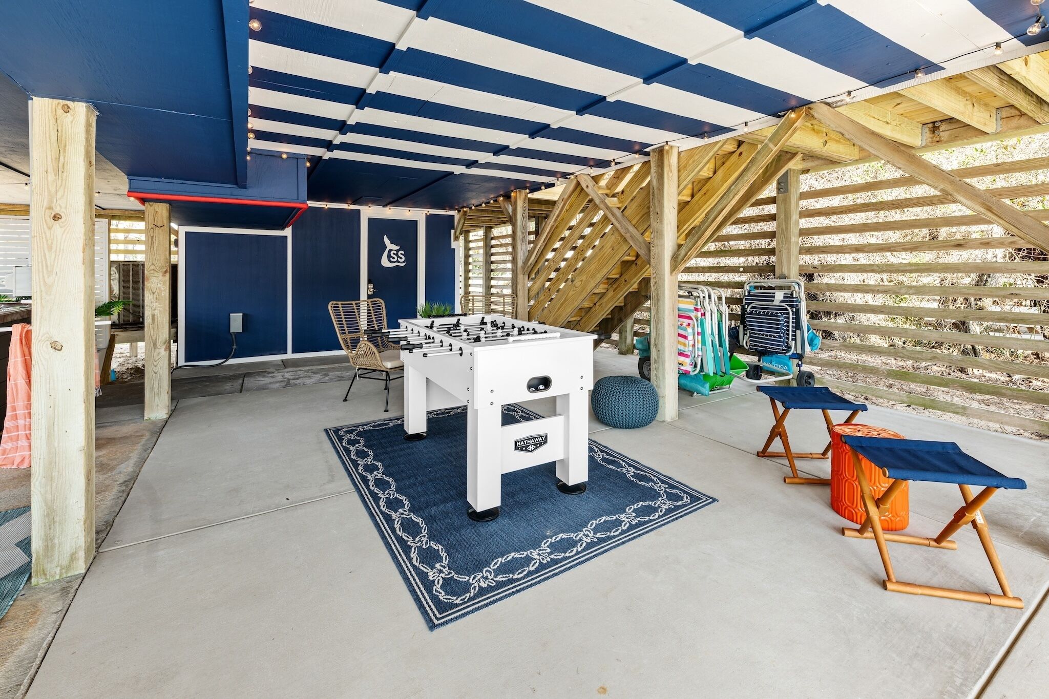 An indoor recreational area with a foosball table, seating, and a wooden climbing structure.