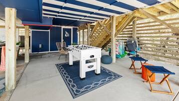 An indoor recreational area with a foosball table, seating, and a wooden climbing structure.