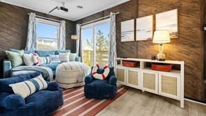A living room with a sofa, armchair, ottoman, and a console table with a lamp. - Beach Cottage · Hot Tub · Rooftop · Movie Room (Kill Devil Hills)