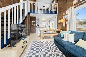 A spacious living area with a staircase, a dining table, and a blue sofa.