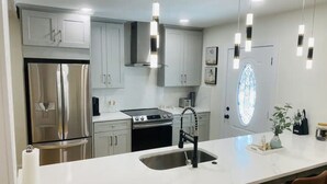 A modern kitchen with stainless steel appliances, a white countertop, and pendant lighting. - Private Pool and Close to Clearwater beach! Perfect for any family! (Clearwater)