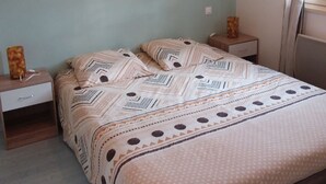 Een slaapkamer met een bed, twee nachtkastjes, een schilderij en een raam met gordijnen.