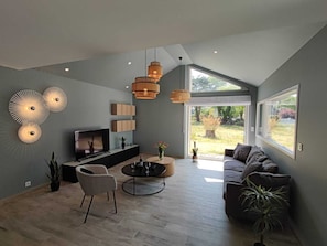 A modern living room with a TV, seating, and a large window.