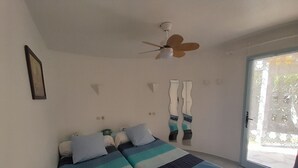 Une chambre à coucher avec un lit, un ventilateur de plafond, une fenêtre et une porte.