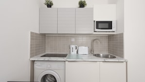 Cocina compacta con lavadora, microondas y pileta.
