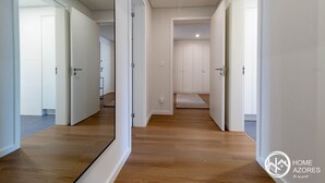 A corridor with wooden flooring leading to a room with a door.