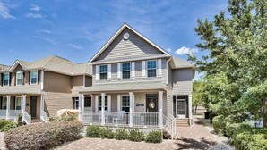 A two-story residential building with a covered porch, multiple windows, and a small front yard with landscaping. - Walk to the Beach ~ Biking Trails (Santa Rosa Beach)